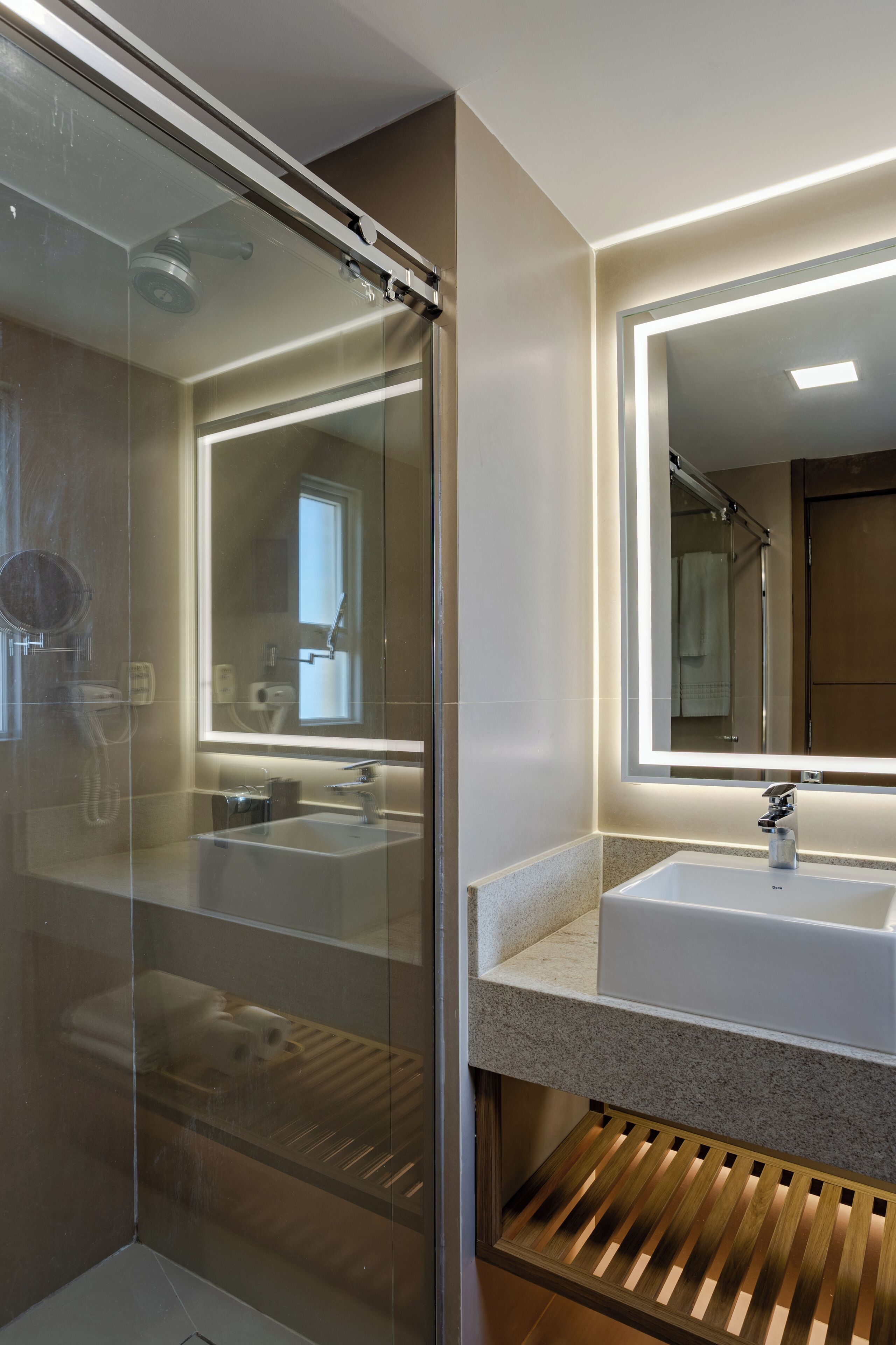 Un baño moderno con cabina de ducha de vidrio, un espejo grande y un lavabo de granito.