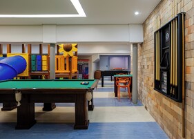 A pool table with a green felt surface, a blue pool table, and a pool table with a white felt surface.