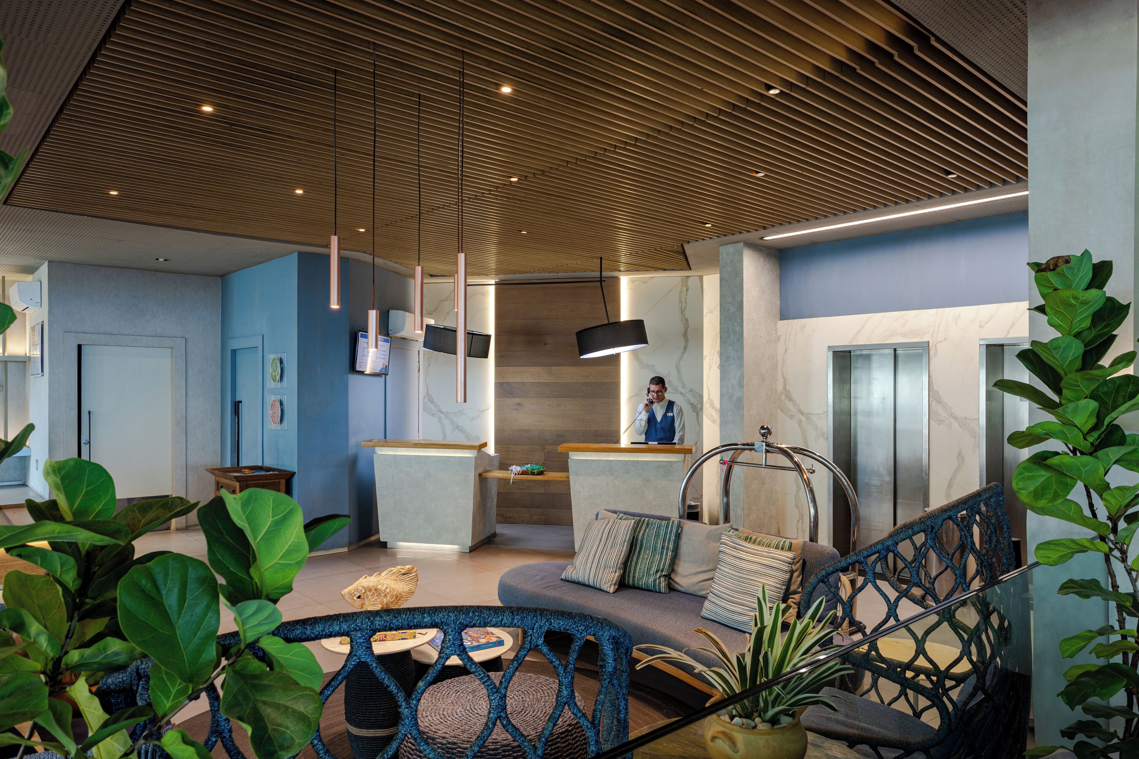 A modern lobby with a reception desk, seating area, and a staircase.