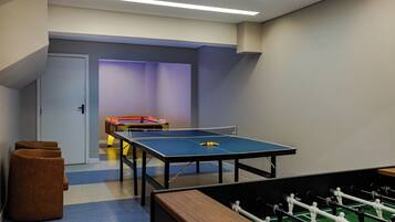 A room with a ping pong table, a foosball table, and a door.