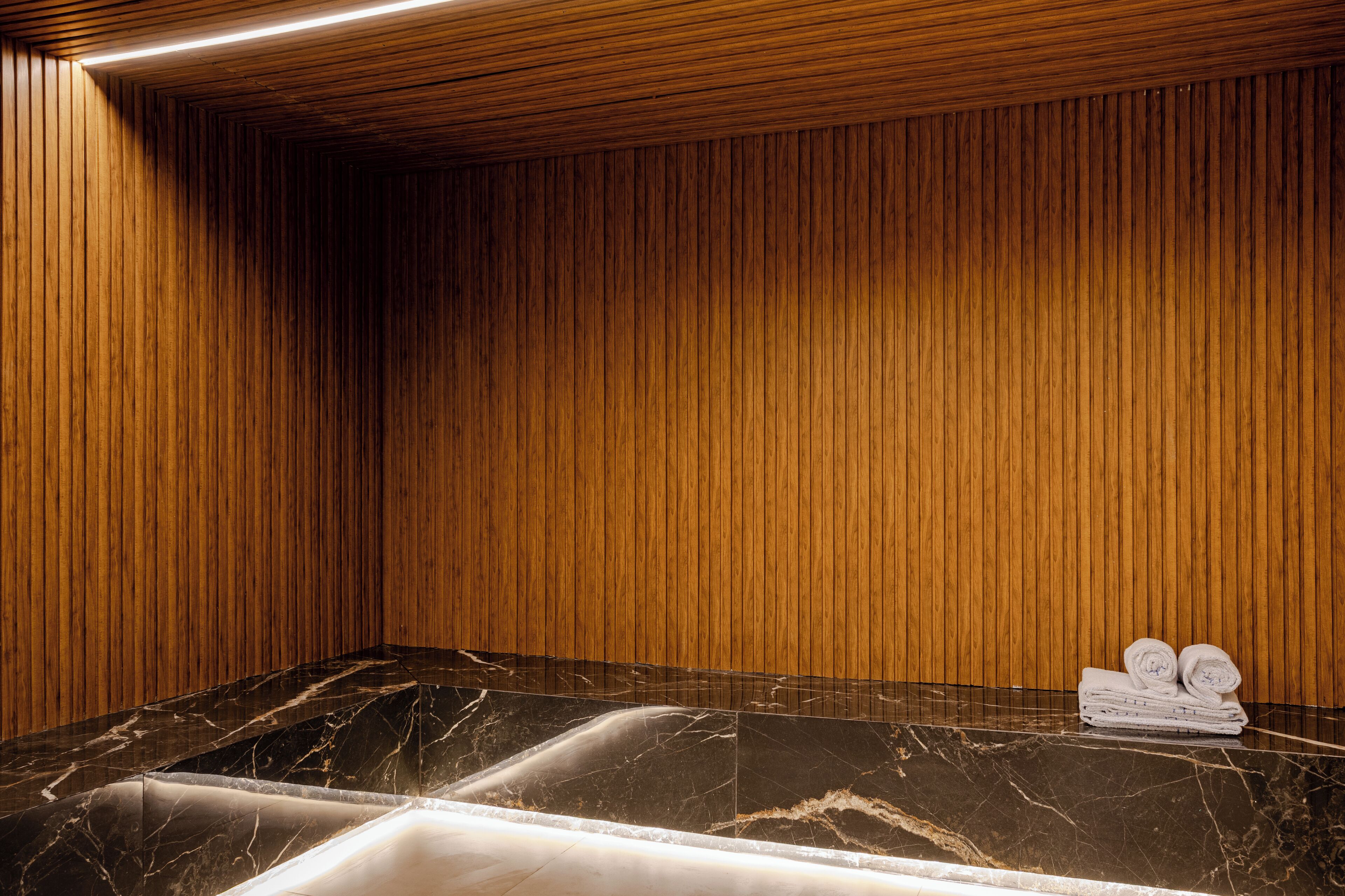 Una habitación con paneles de madera, encimera de mármol y toallas.