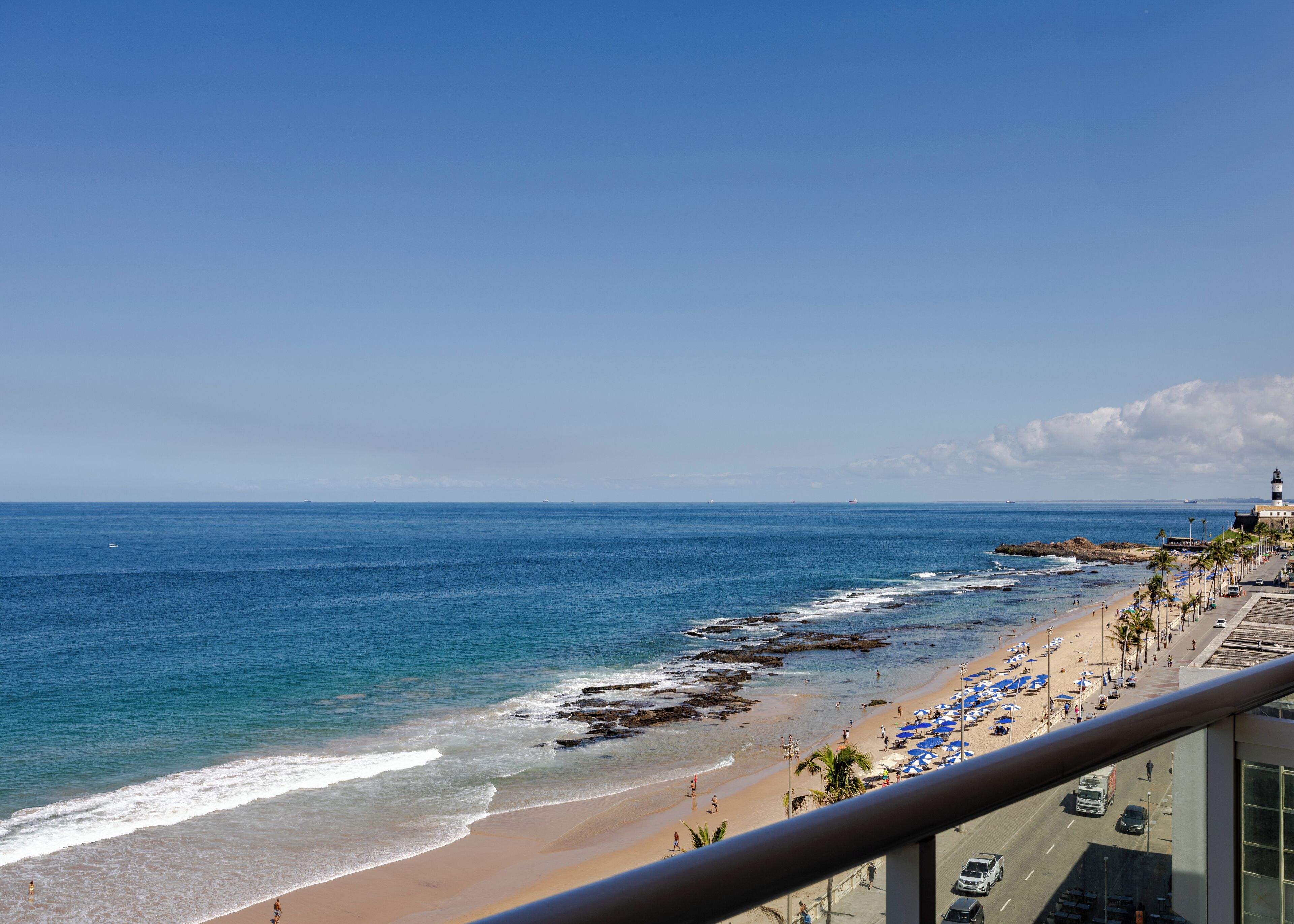 A coastal view with a beach, ocean, and a lighthouse.