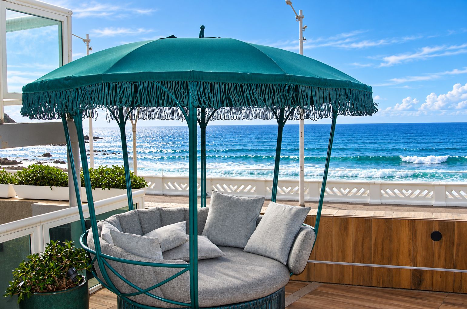 Un área de estar al aire libre frente al mar, con una silla colgante y un toldo.