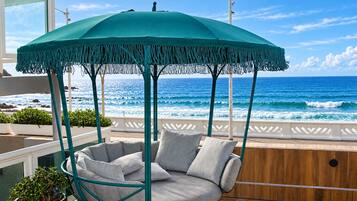 Un área de estar al aire libre frente al mar, con una silla colgante y un toldo.