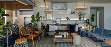 Un salon moderne comprenant un canapé, des fauteuils, une table basse et des étagères ornées d’objets décoratifs.