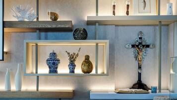 Een modern interieur met een blauw patatoffel, planken met decoratieve objecten, en een kruis.