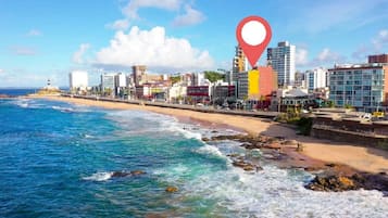 A coastal cityscape with a beach, buildings, and a lighthouse.