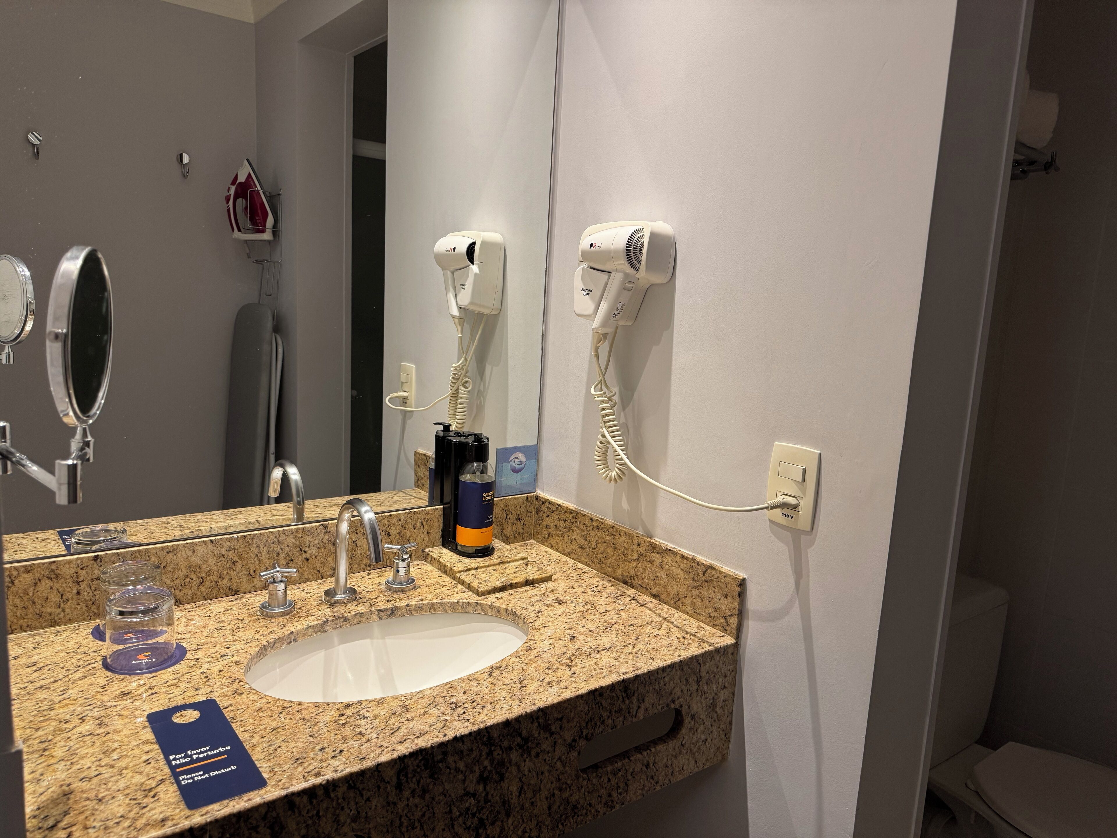 Un baño con lavamanos de encimera de granito, espejo, secador de pelo y teléfono.