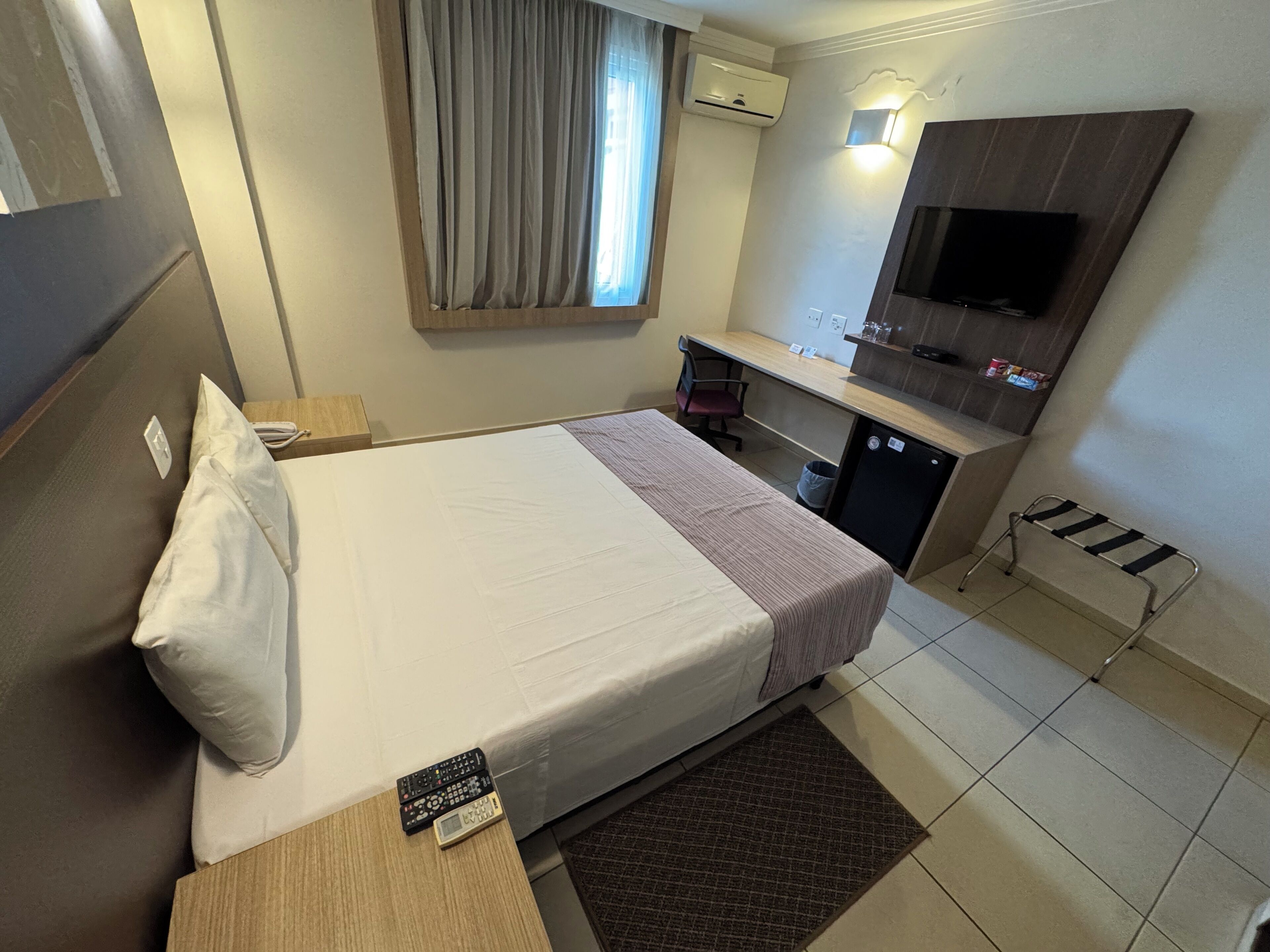 Una habitación de hotel con una cama, un escritorio, un televisor y una pequeña cocina.