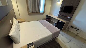 Una habitación de hotel con una cama, un escritorio, un televisor y una pequeña cocina.