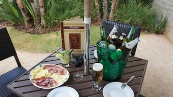 A table set outdoors with a menu, bottles, glasses, and plates of food.