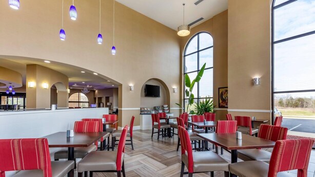 Un restaurante espacioso con techos altos, ventanas amplias y luminarias modernas.