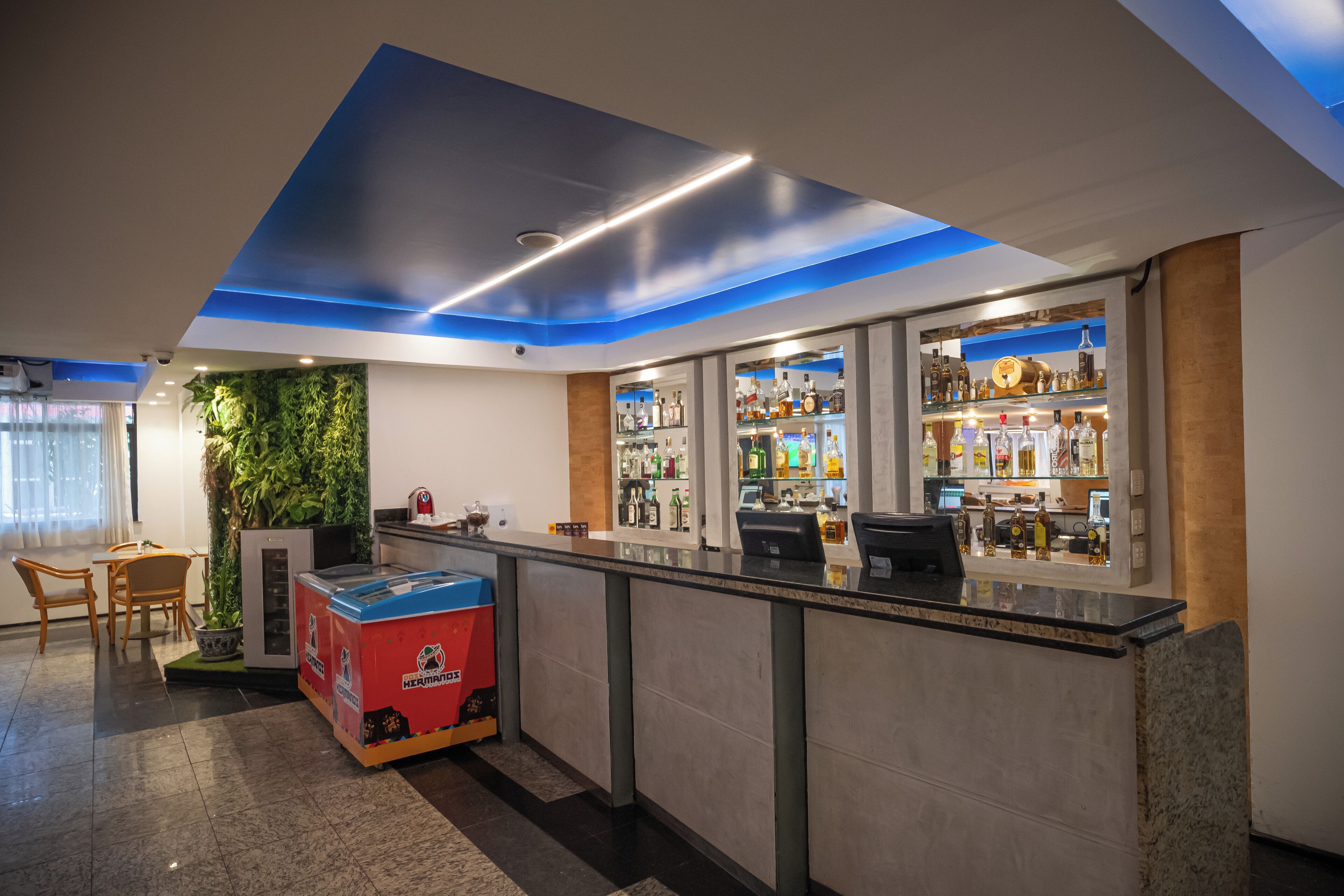 Un moderno bar con una barra, estantes llenos de botellas de licor y un área de estar con una mesa y sillas.