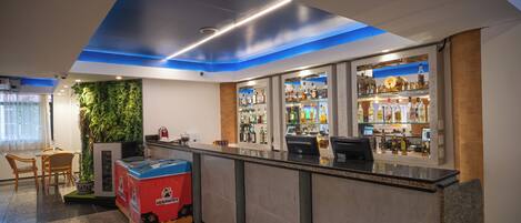 A modern bar area with a counter, shelves of liquor bottles, and a seating area with a table and chairs.