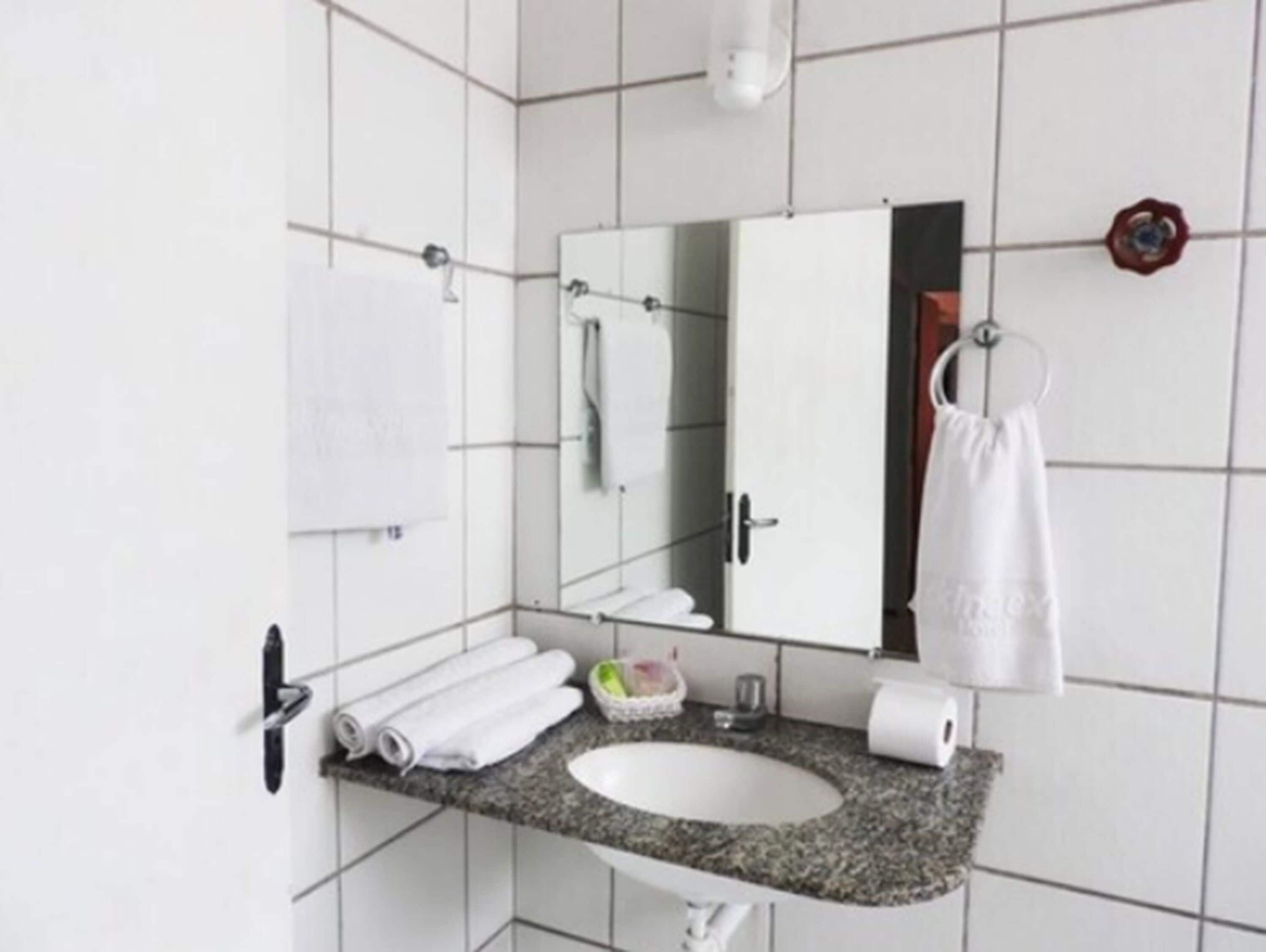 Un baño moderno con encimera de granito, lavamanos blanco y un espejo grande.