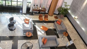Un'ampia hall con diverse opzioni di seduta, tra cui divani e poltrone, disposte attorno a un tavolino con un oggetto decorativo.