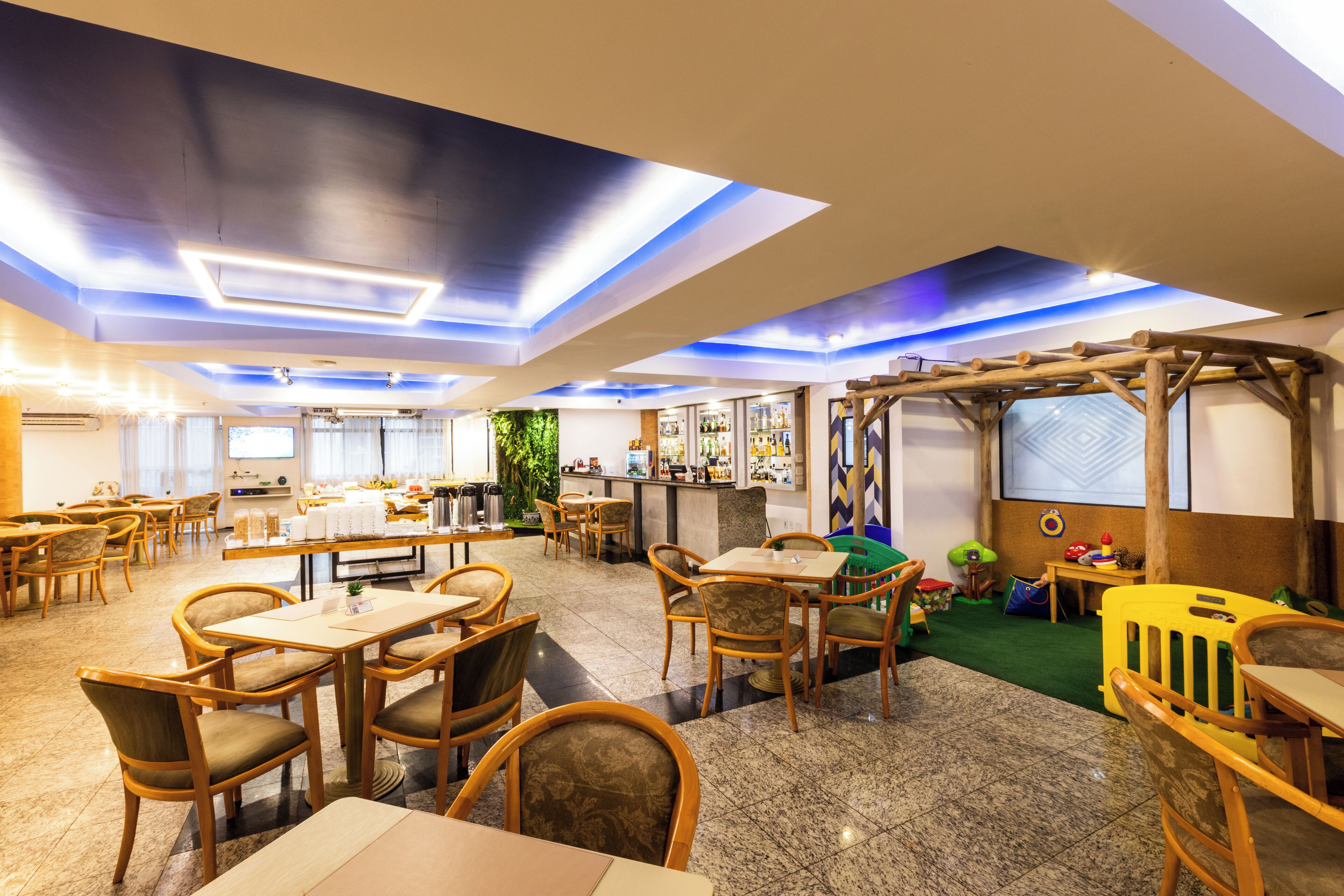 Un restaurante espacioso con mobiliario de madera, una zona de bar y un área de juegos para niños.