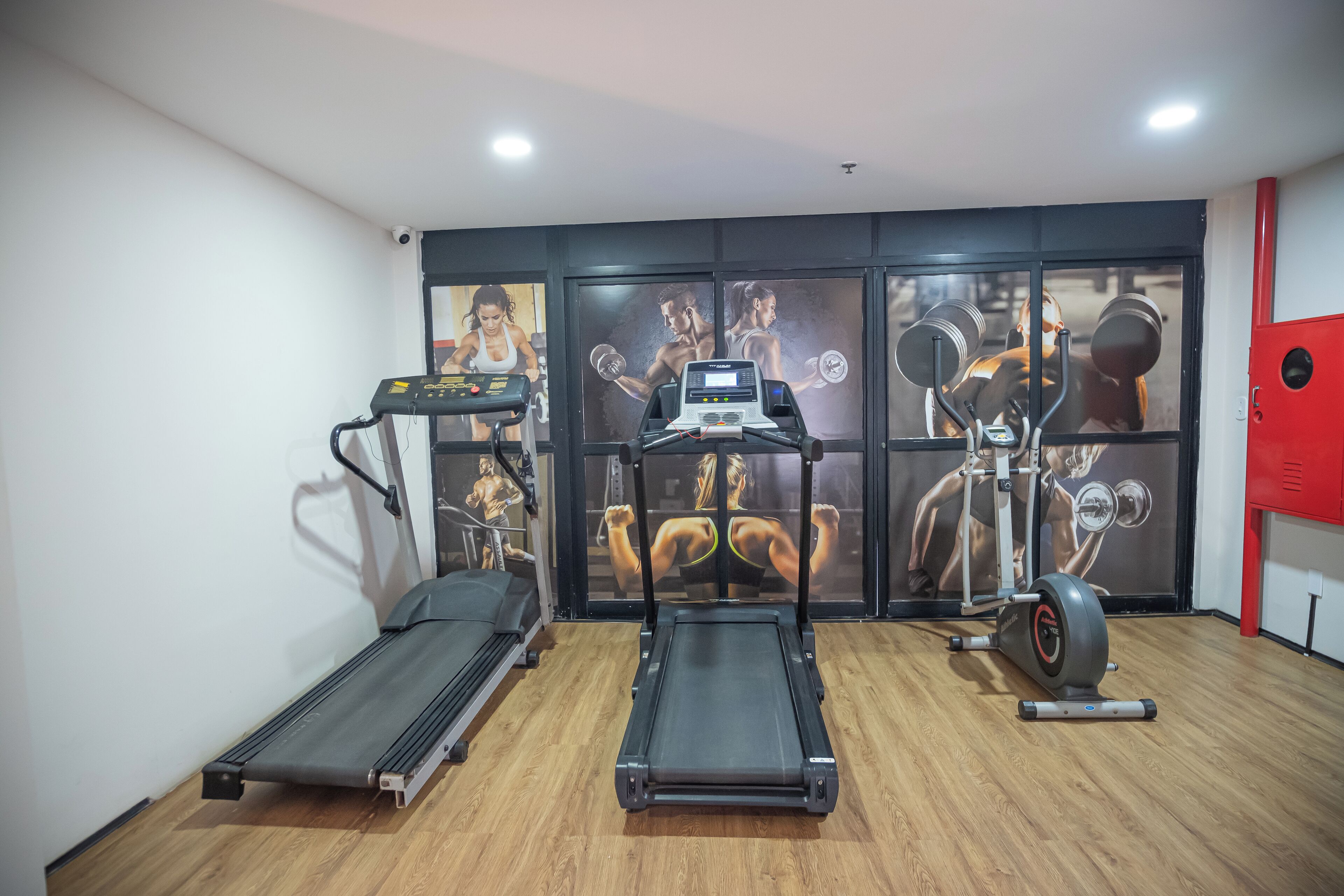 A gym with treadmills, a stationary bike, and a wall with fitness posters.