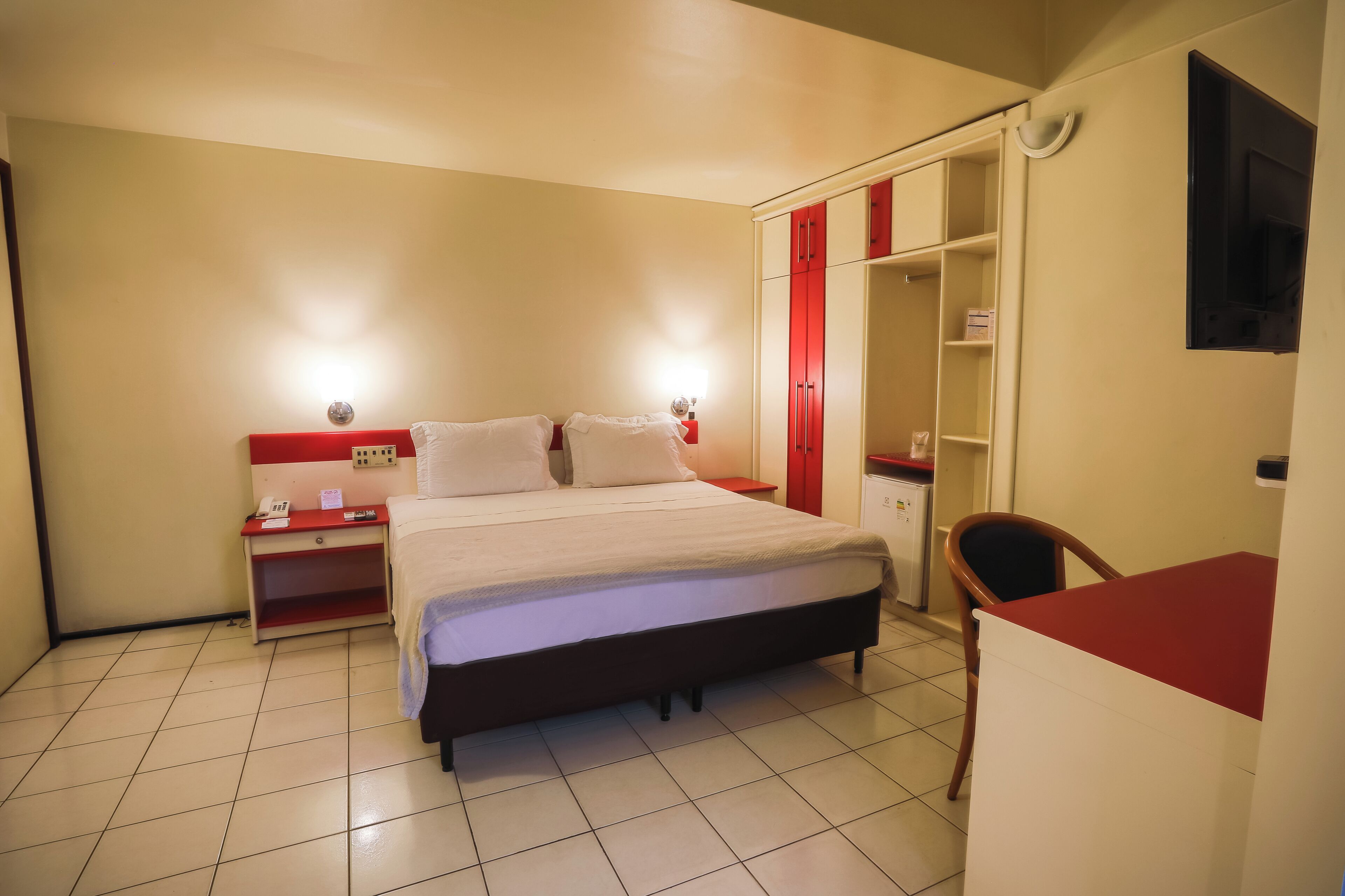 A hotel room with a bed, bedside table, and a wardrobe.