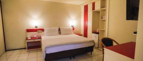 Una habitación de hotel con cama, mesita de noche y armario.