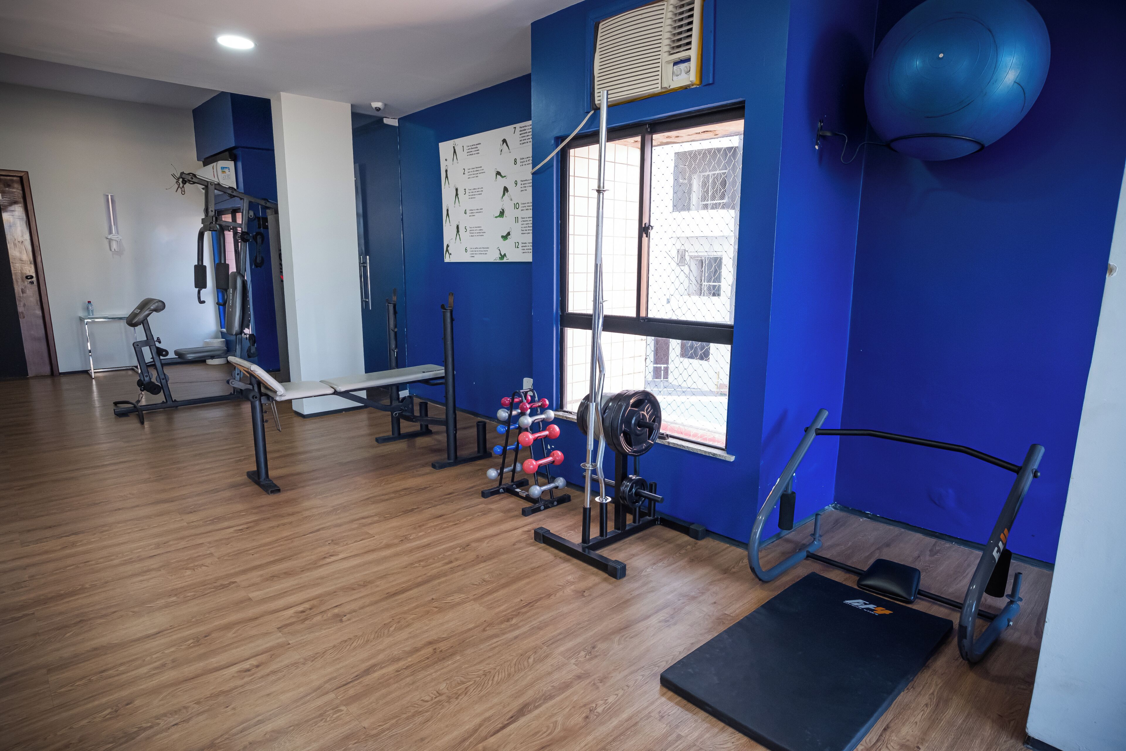 A gym with exercise equipment, a window, and a blue wall.