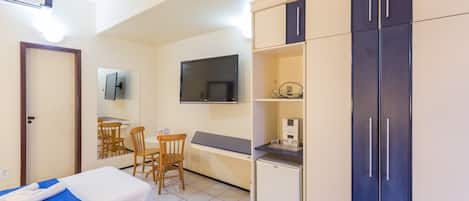 A hotel room with a bed, a desk, a chair, a TV, and a wardrobe.