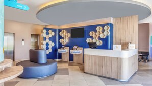 A modern reception area with a curved desk, digital check-in counters, and directional signs for Armadillo, Cd. Valles, and Xilitla.