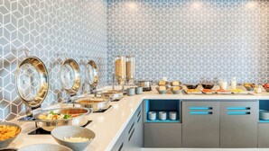 A buffet setup with various food items and serving utensils.