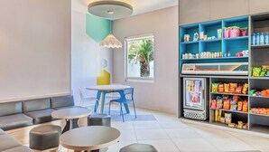A modern interior with a seating area, a table, and a beverage refrigerator stocked with snacks.