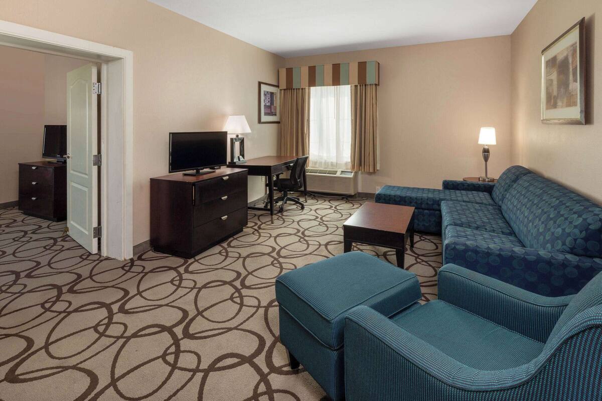 Ein Hotelzimmer mit einer Couch, einem Fernseher, einem Schreibtisch und einem Schminktisch.