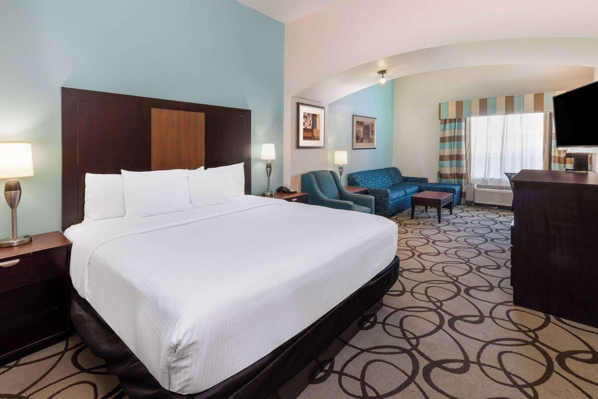 Ein Hotelzimmer mit einem großen Bett, einem Schreibtisch, einem Stuhl und einem Fernseher.
