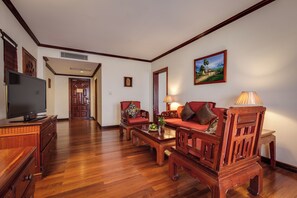 A spacious living room with wooden furniture, a television, and a painting on the wall.