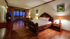 A spacious bedroom with a large wooden bed, a television, and a nightstand with a lamp. - Angkor Paradise Hotel (Siem Reap)