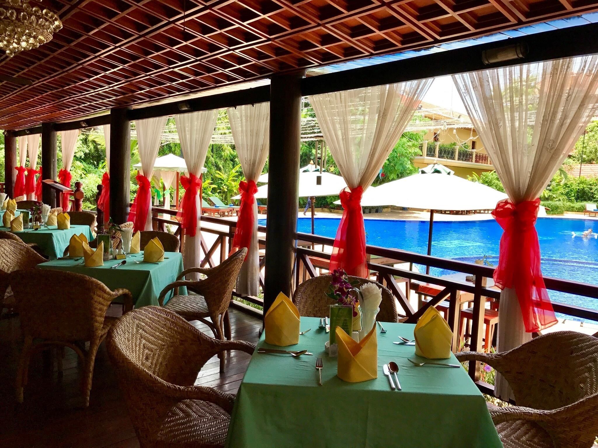A restaurant with tables set for dining, overlooking a pool.