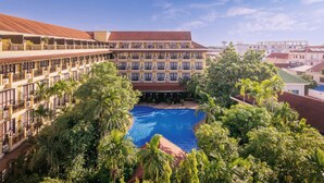 A hotel with a large pool surrounded by lush greenery and multiple balconies. - Angkor Paradise Hotel (Siem Reap)