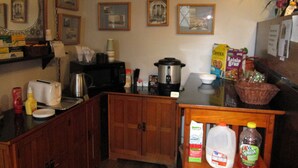 A kitchen with wooden cabinets, a microwave, a coffee maker, and various kitchen items on the counter. - Jim Butler Inn & Suites (Tonopah)