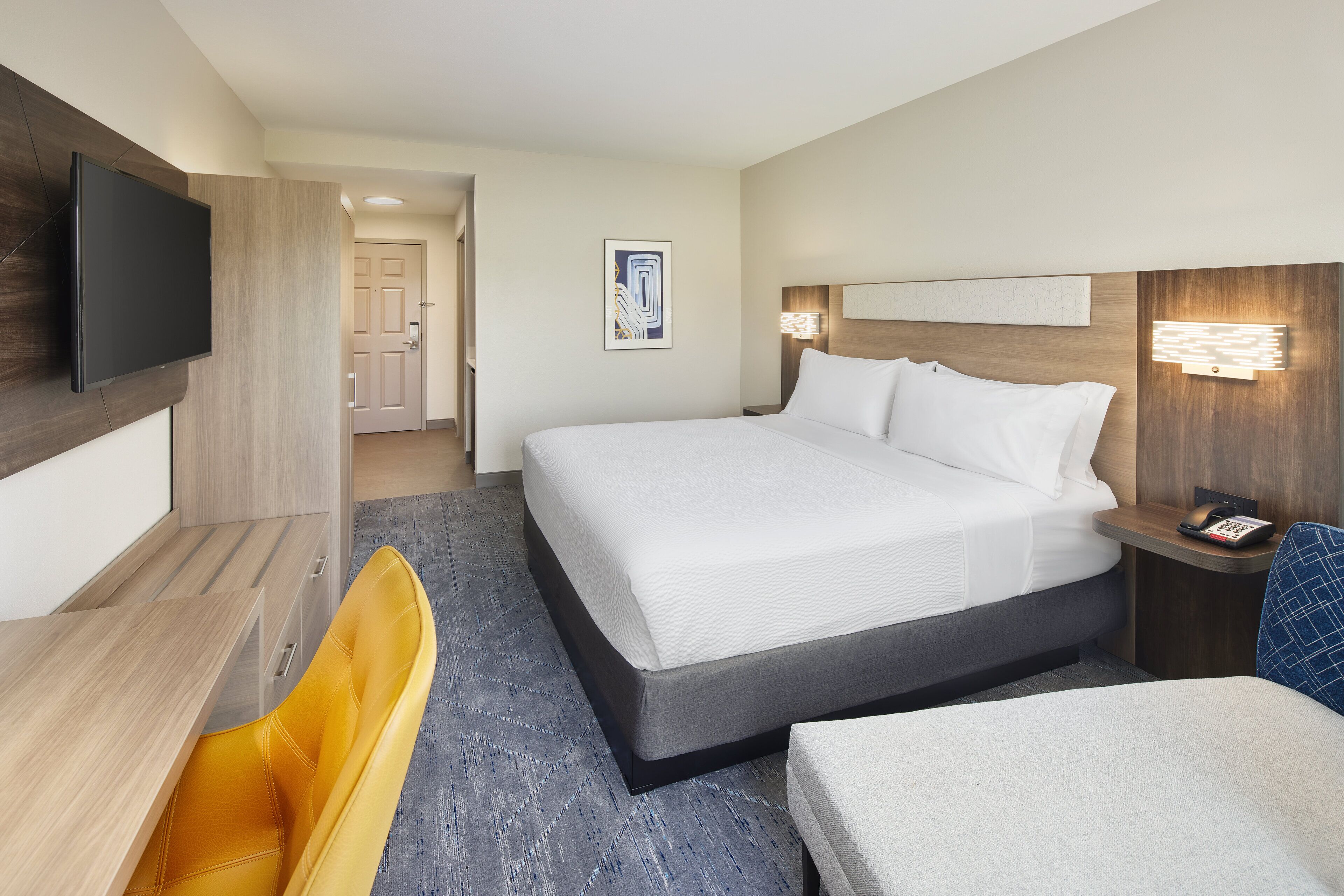 A hotel room with a bed, a television, a desk, and a chair.