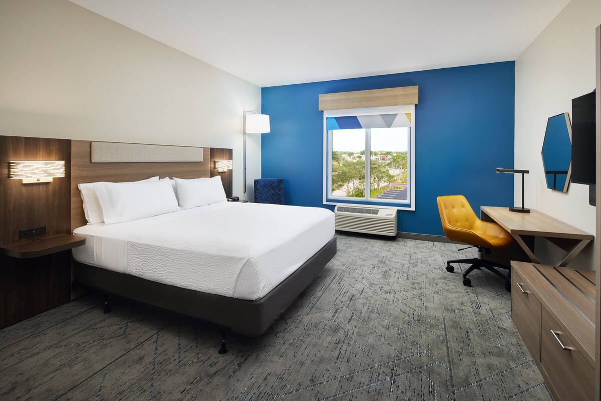 Een hotelkamer met een groot bed, een bureau, een stoel en een raam met uitzicht.