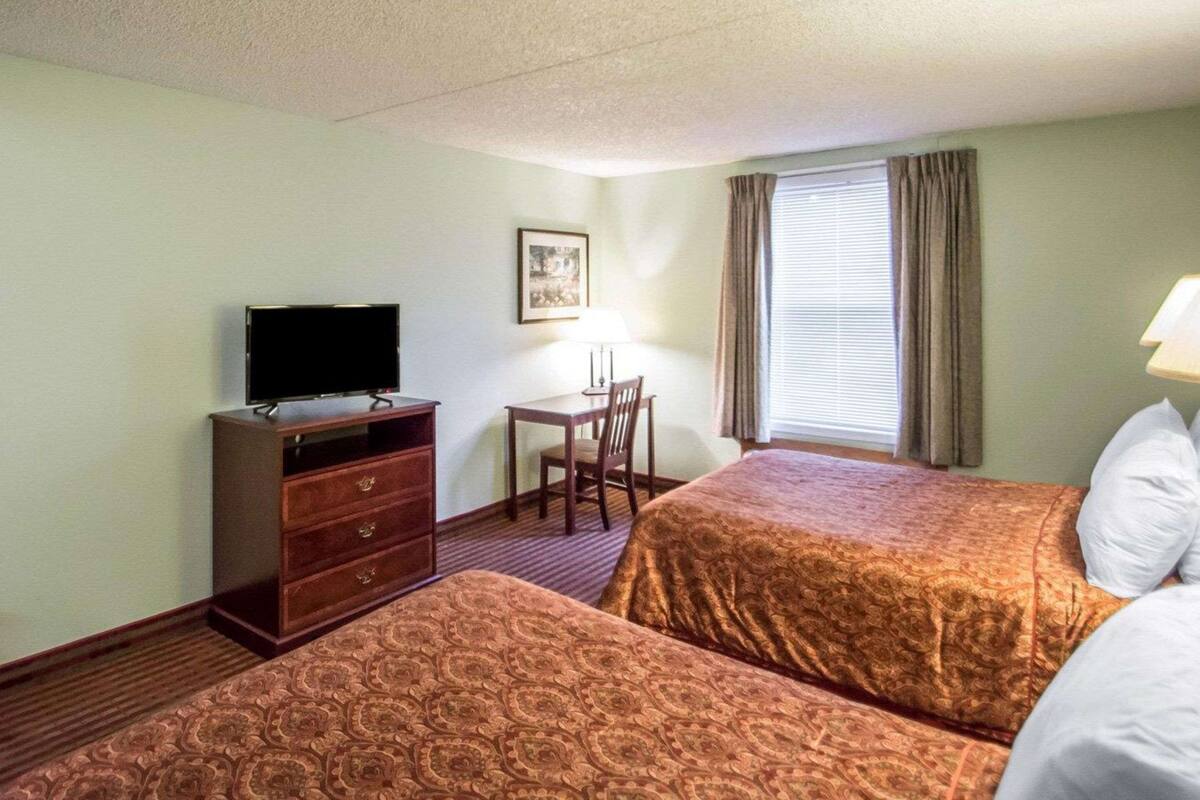 Una habitación de hotel con dos camas, televisión, escritorio y una silla.