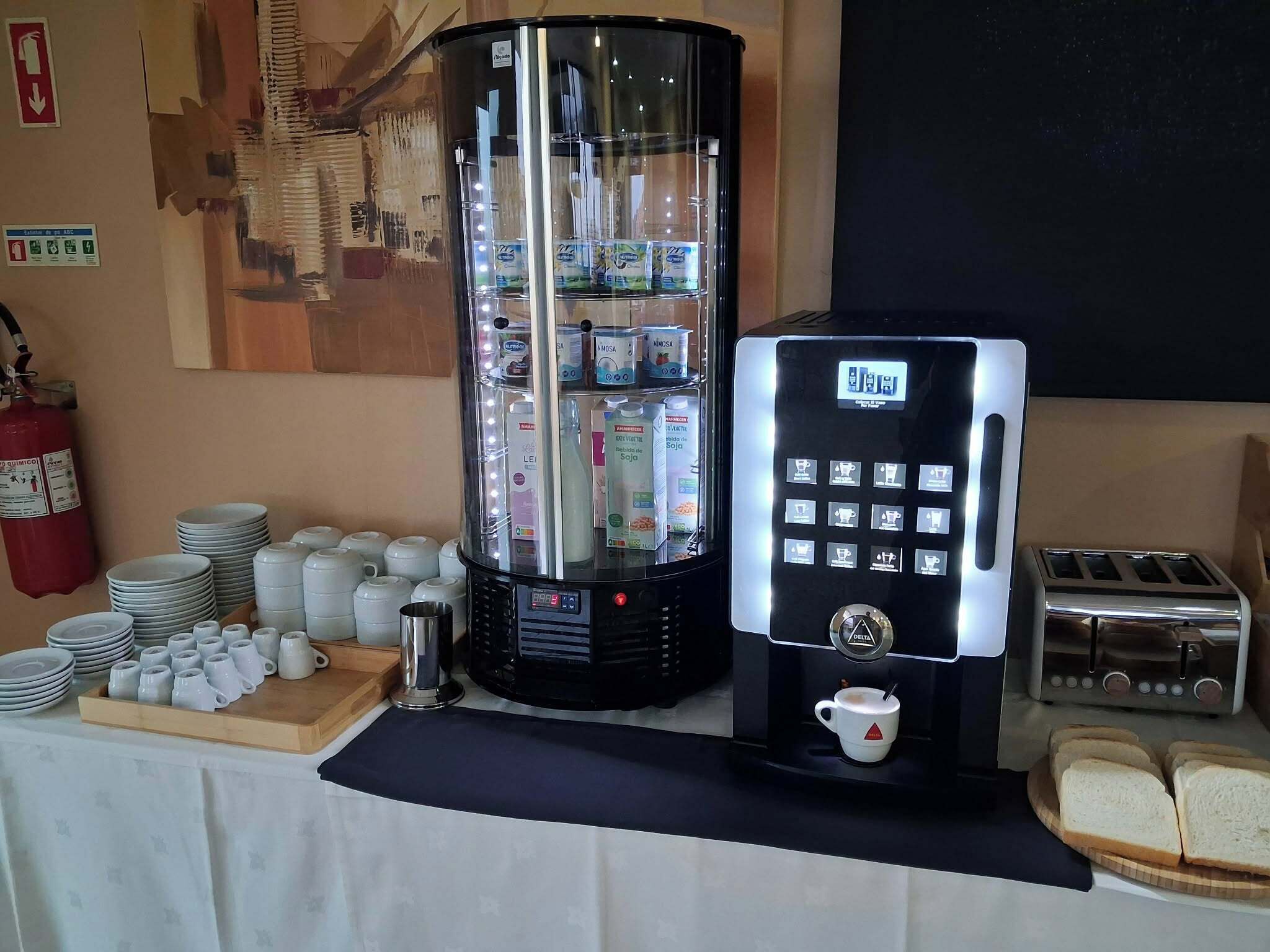 A coffee station with a coffee machine, a toaster, and a display of milk cartons.