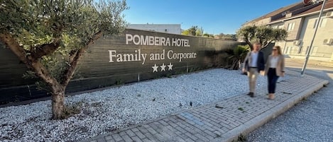 Un cartel de hotel con el nombre 'POMBEIRA HOTEL' y las palabras 'Familia y Corporativo', junto con tres estrellas.