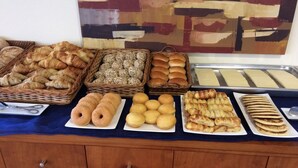 Een buffet met diverse gebakken producten, waaronder croissants, broodjes en gebak.