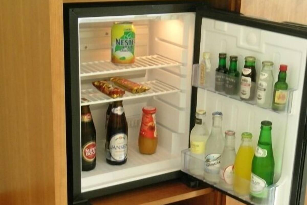 A small refrigerator with shelves containing various beverages and condiments.