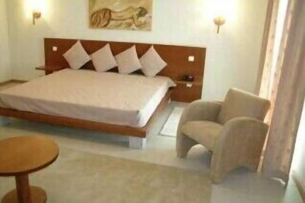 A bedroom with a large bed, a bedside table, a chair, and a small table.