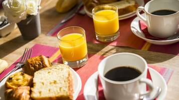 A breakfast setting with orange juice, coffee, croissants, and pastries on a table.