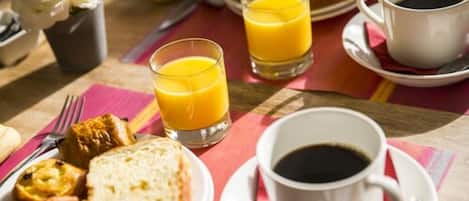 A breakfast setting with orange juice, coffee, croissants, and pastries on a table.