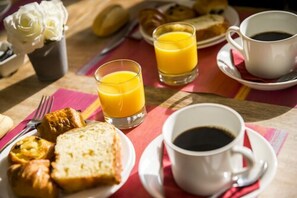 A breakfast setting with orange juice, coffee, croissants, and pastries on a table.