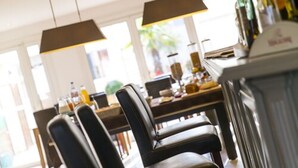 Un comedor con sillas de cuero, una mesa de madera e iluminación colgante.
