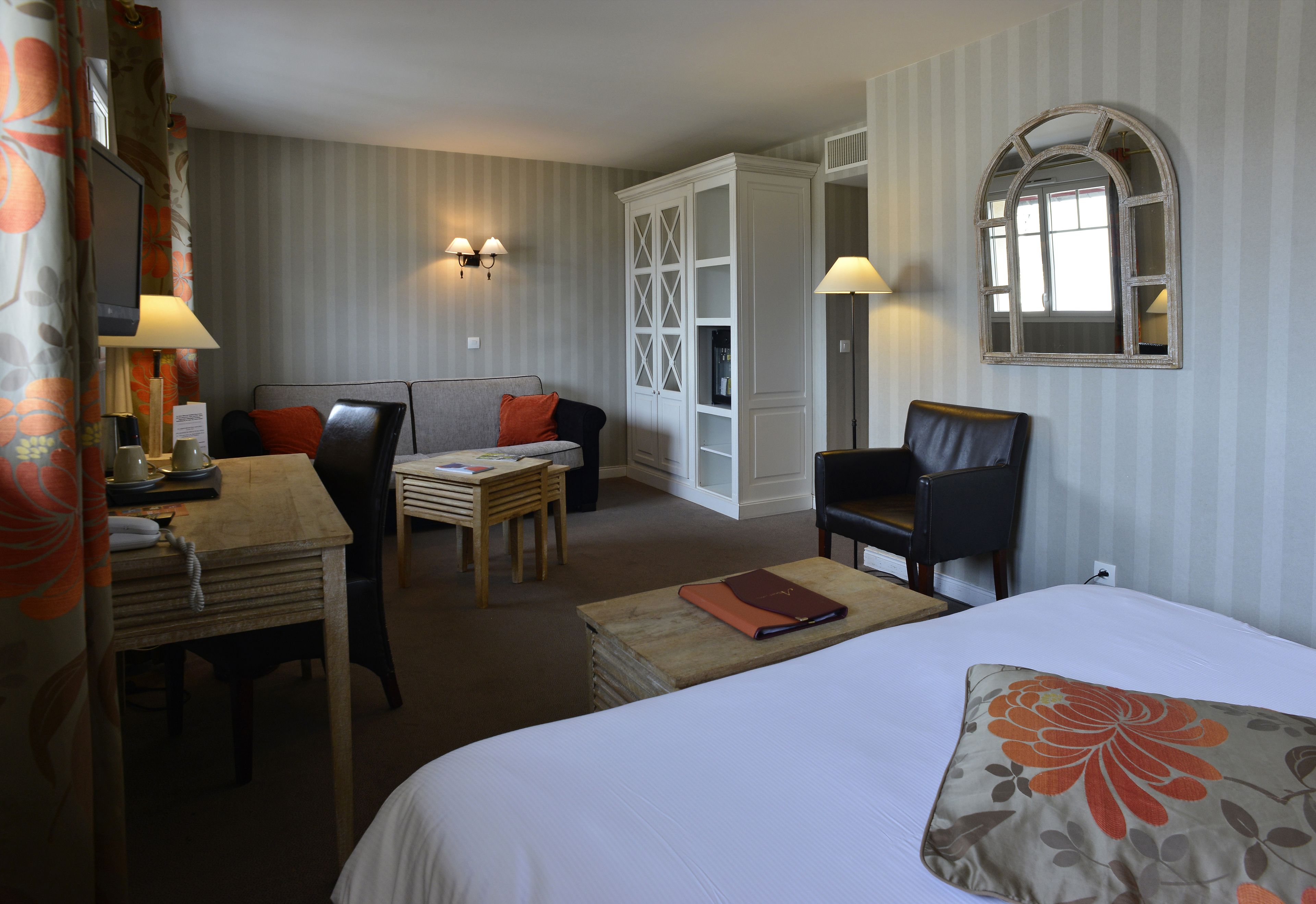 A hotel room with a bed, a desk, a chair, a sofa, and a wardrobe.