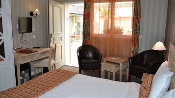 Habitación de hotel con cama, escritorio, dos sillas, televisor y ventana con cortinas.